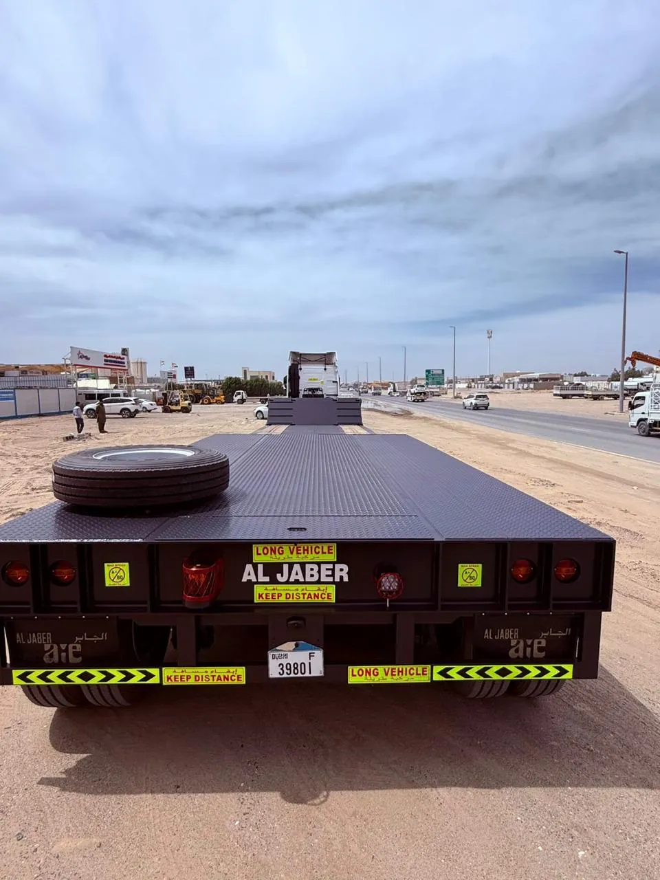 Rear view of an Al Jaber low-bed trailer with reflective markings parked alongside a UAE highway