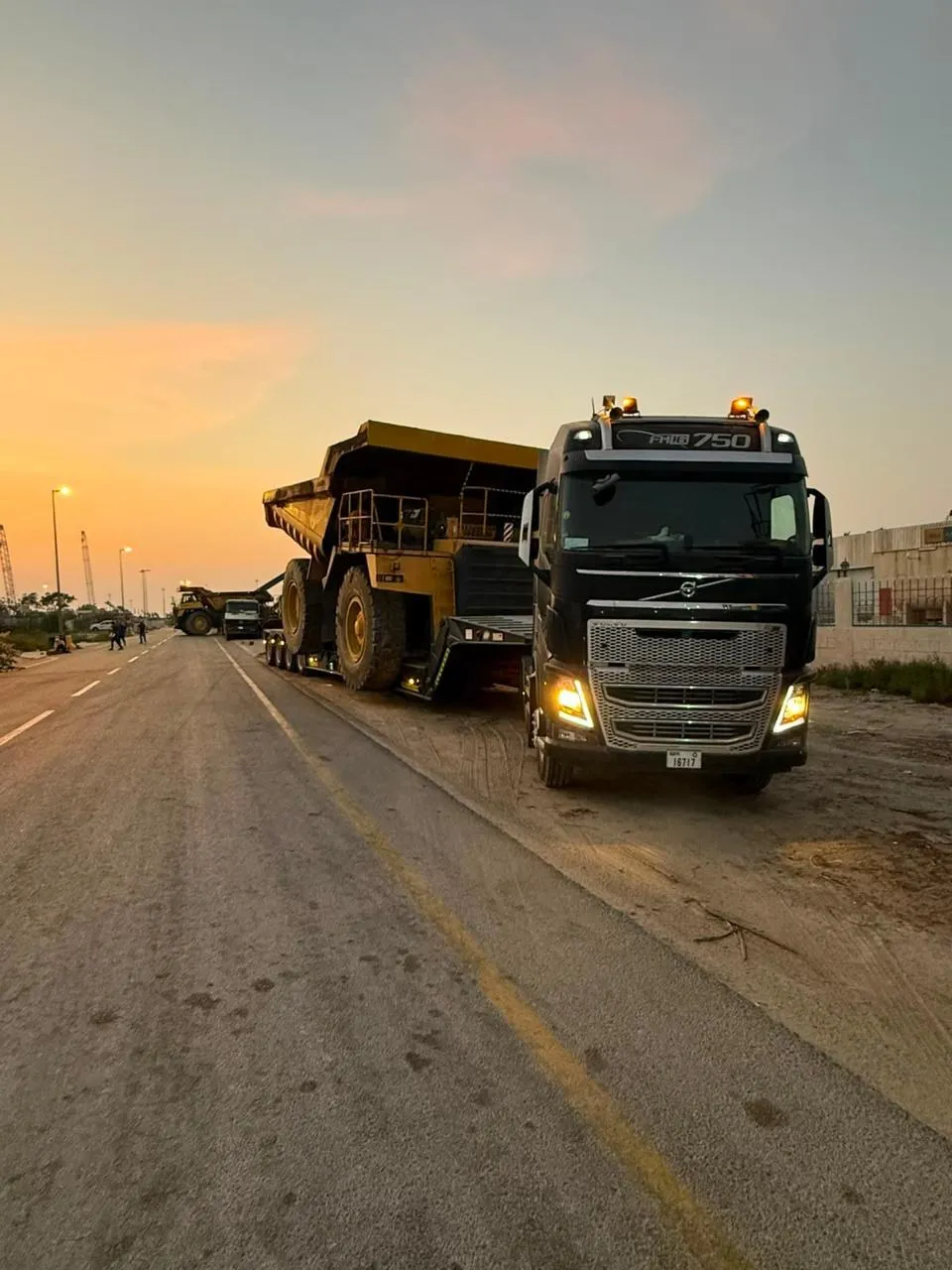 Volvo FH16 750 prime mover hauling a rigid dump truck on a lowbed trailer at sunset