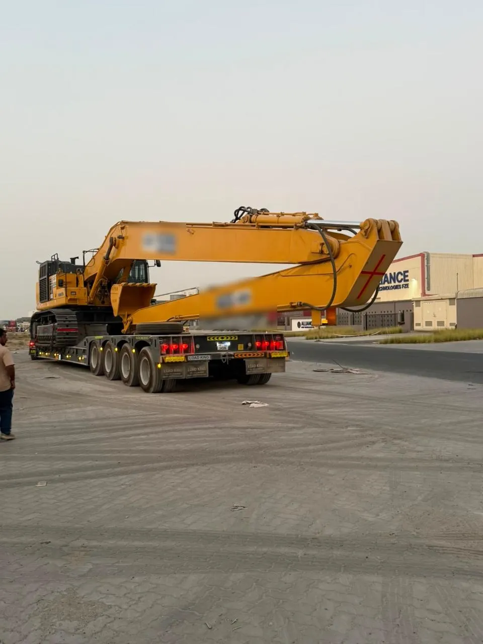 Komatsu PC850 long-reach excavator secured on a 4-axle lowbed trailer on a Dubai industrial street
