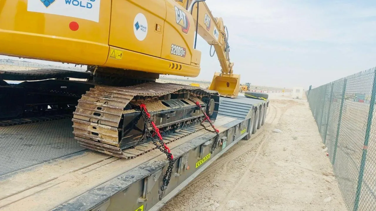 CAT 320D3 tracked excavator chained down on a low-bed trailer deck at a UAE construction site